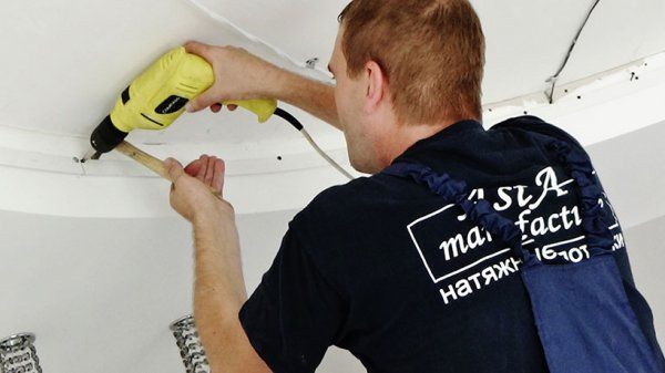 спеціаліст АстаМ встановлює натяжну стелю